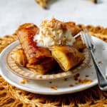 miso turon stacked on a plate with vanilla ice cream and toasted coconut with a fork.