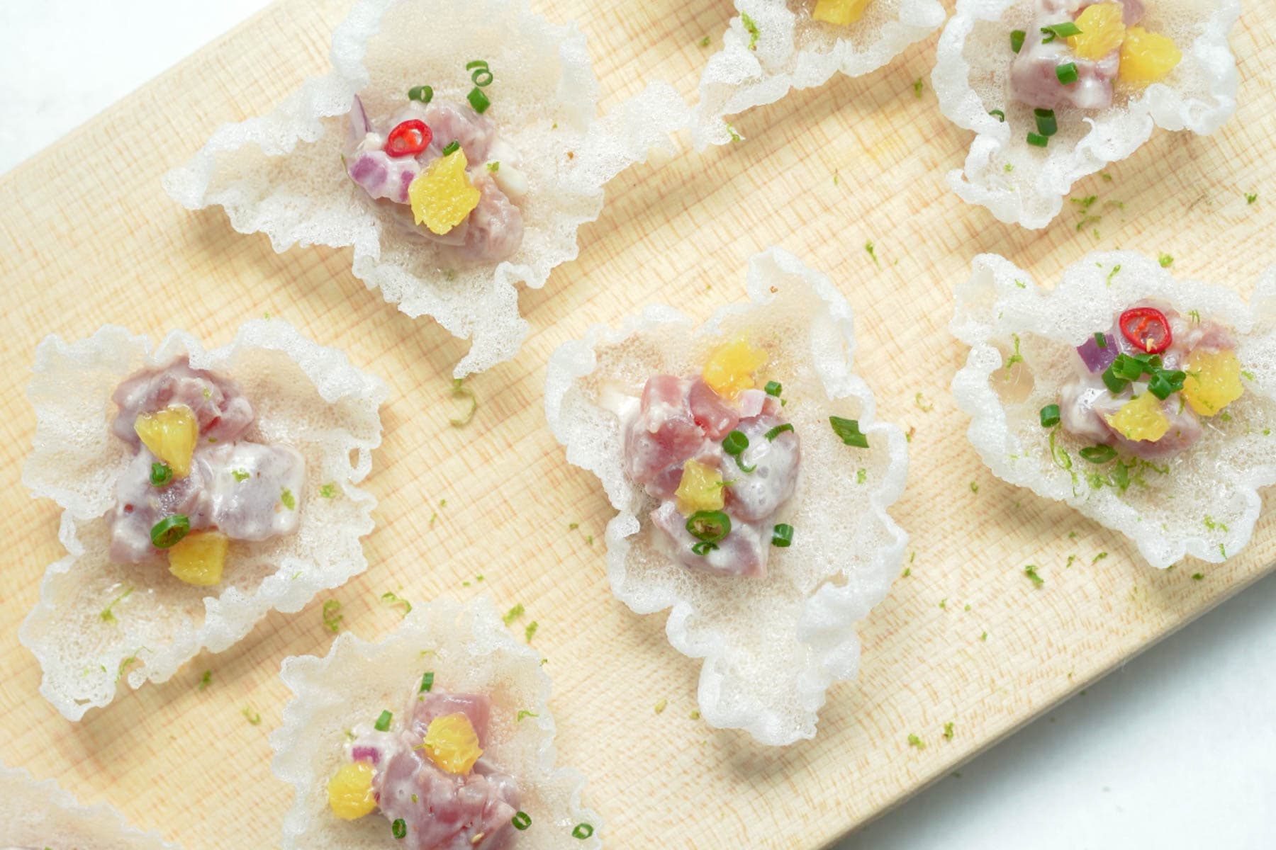 kinilaw in rice paper wrapper on cutting board.