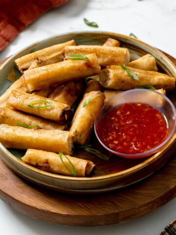 lumpia served on a platter with a sweet chili sauce.