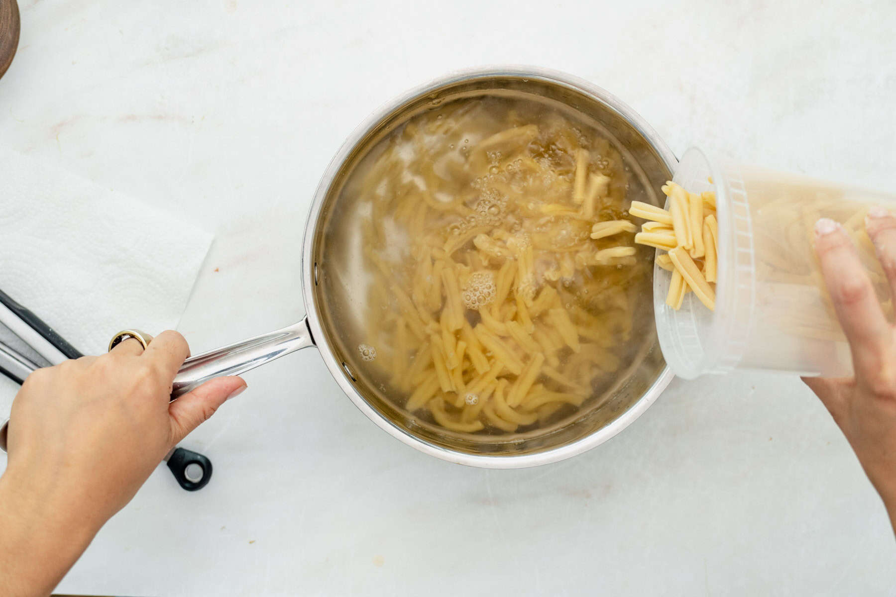 adding pasta to boiling water in a pot.
