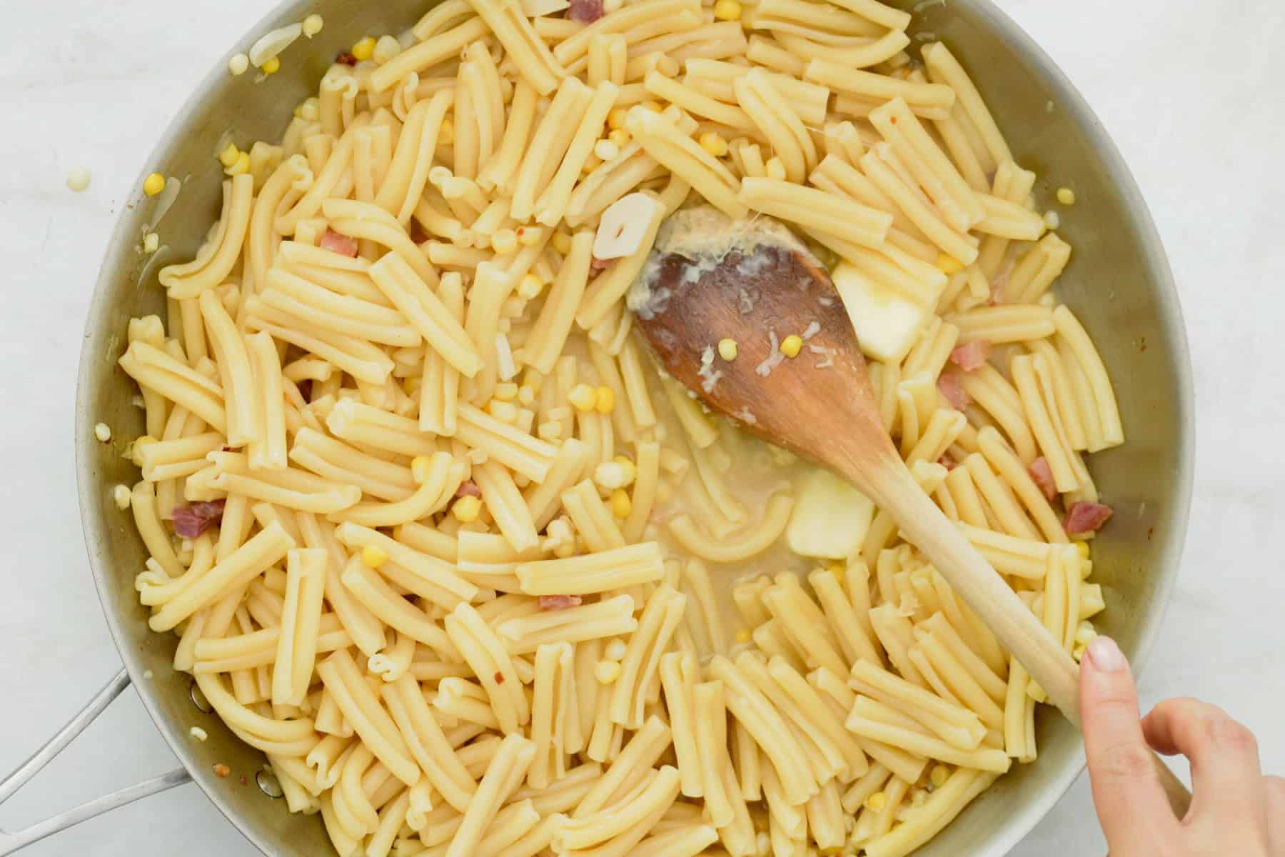 tossing pasta with the rest of the ingredients with a wooden spoon.