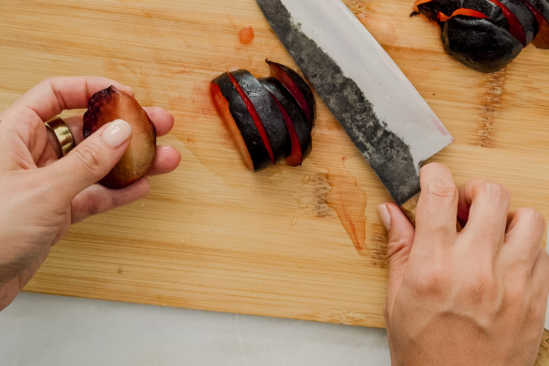 holding sliced plum on cutting board with knife.