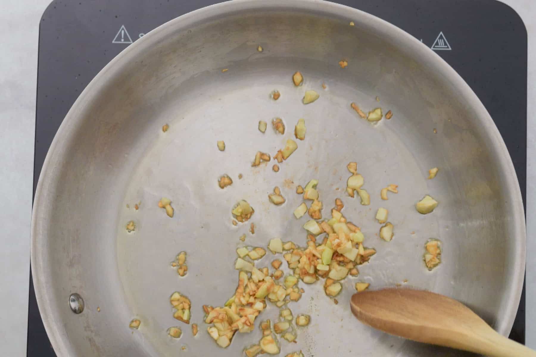 frying garlic in a stainless steel pan.
