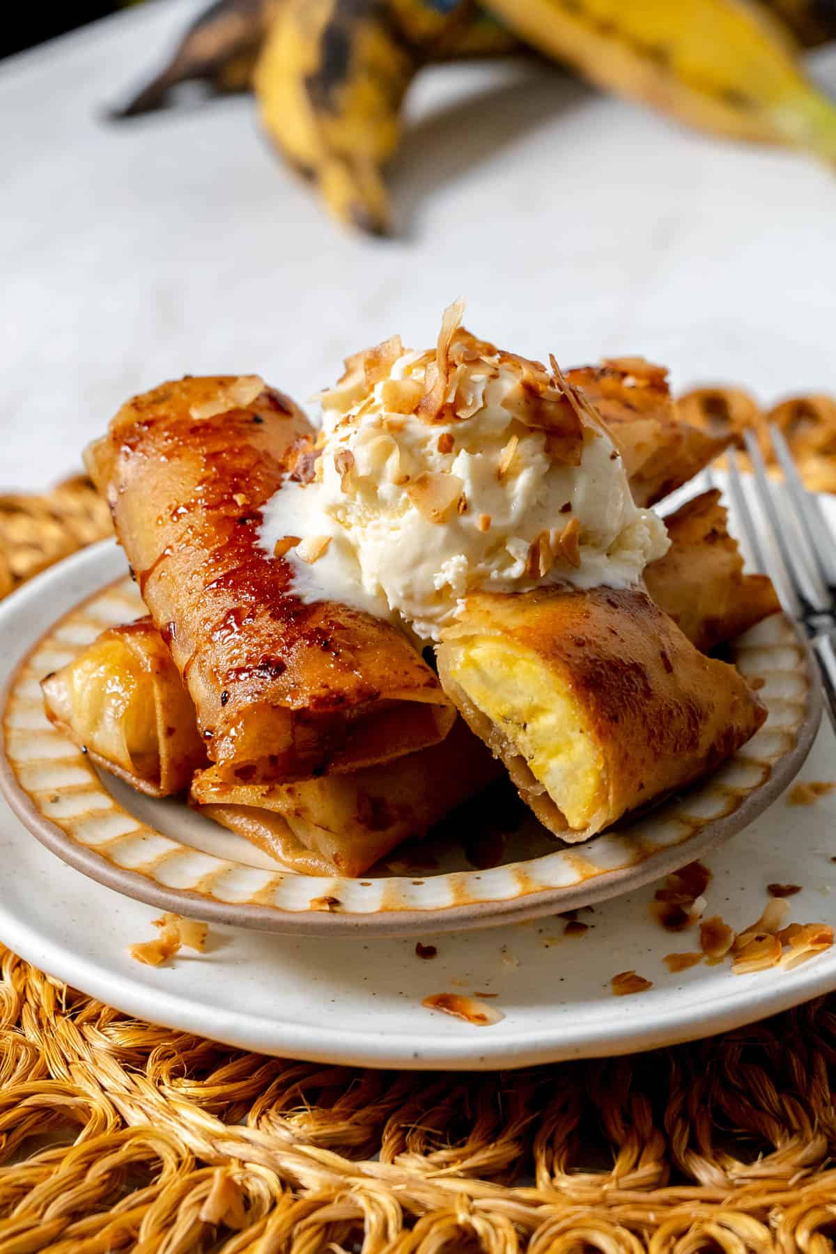 miso turon stacked on a plate with vanilla ice cream and toasted coconut with a fork.