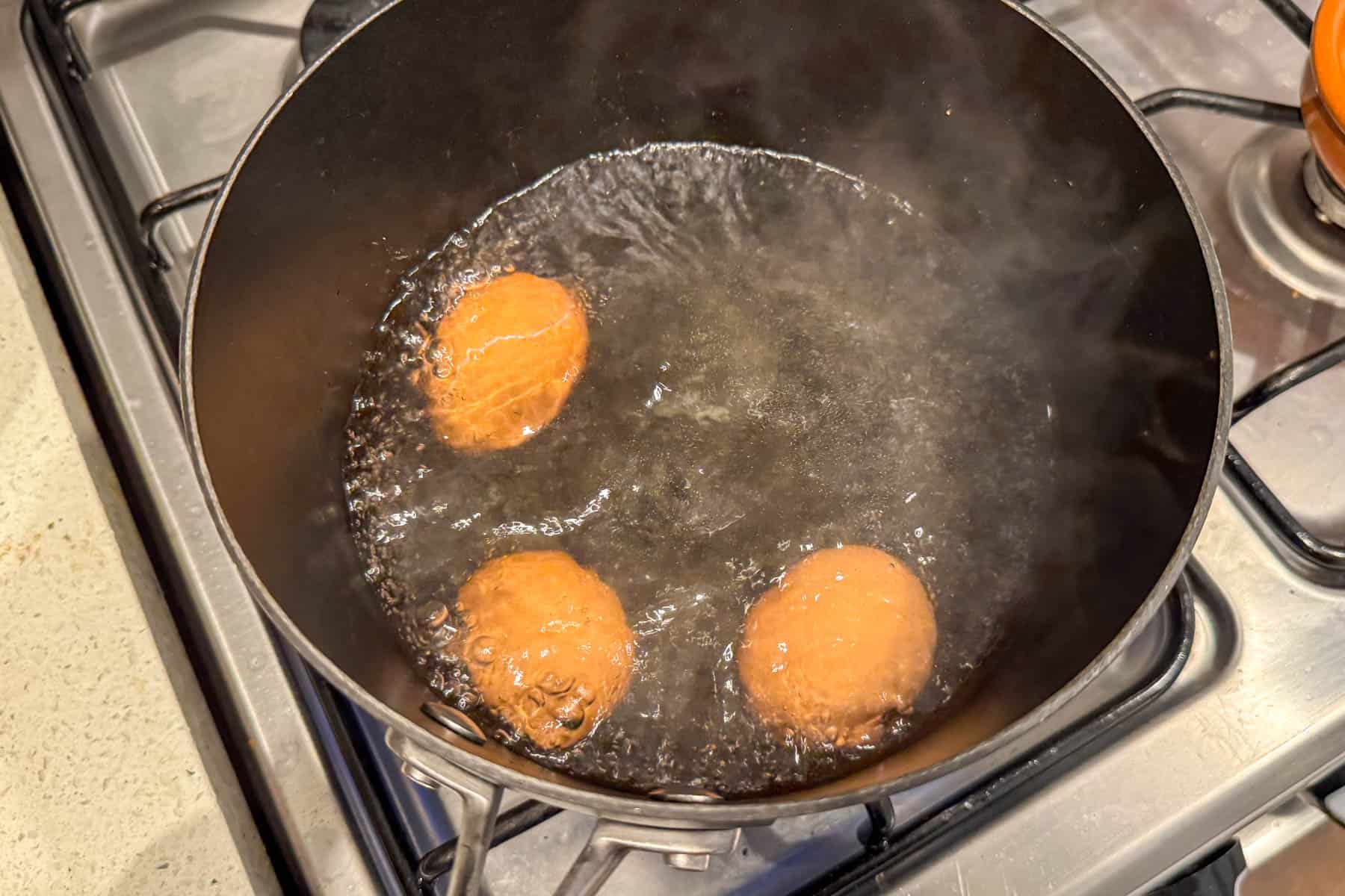 3 eggs boiling in pot.