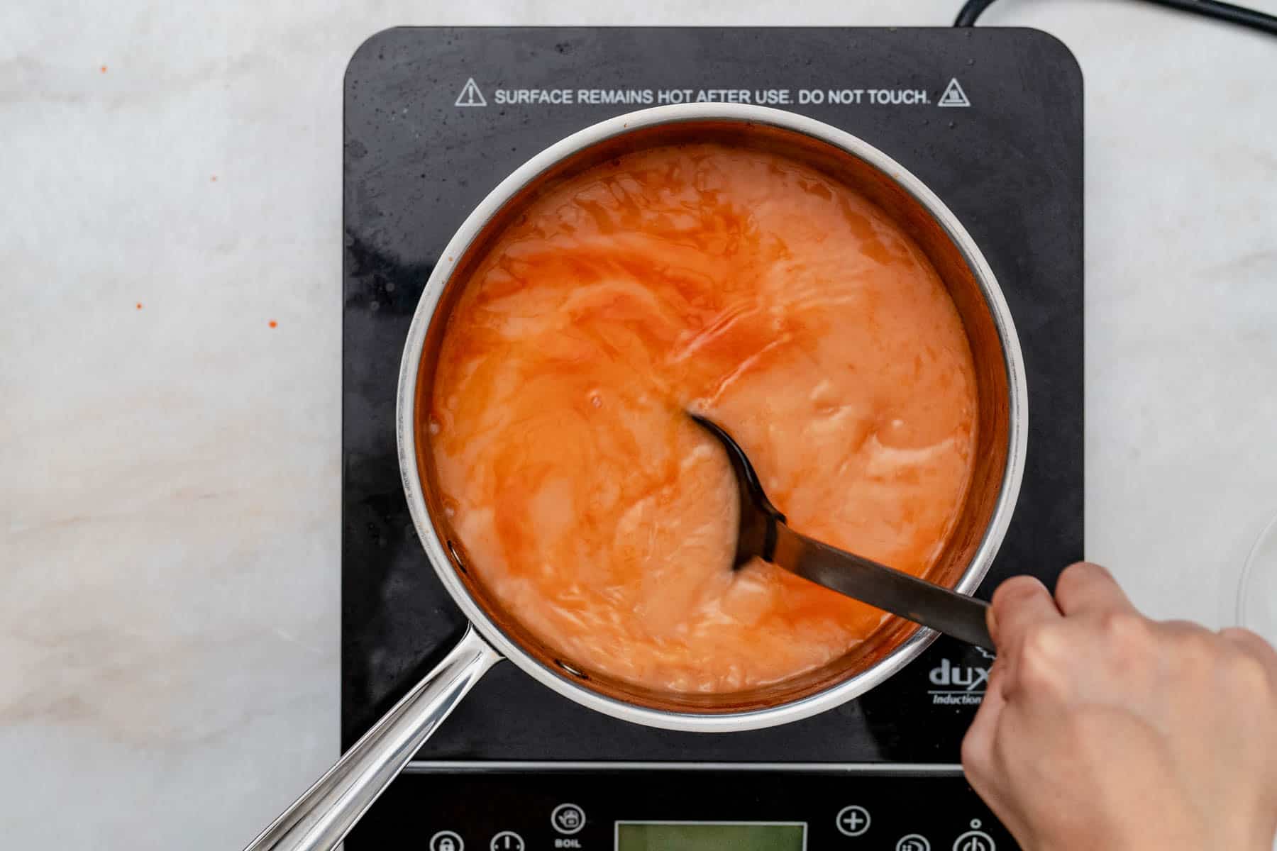 stirring sauce with a spoon.