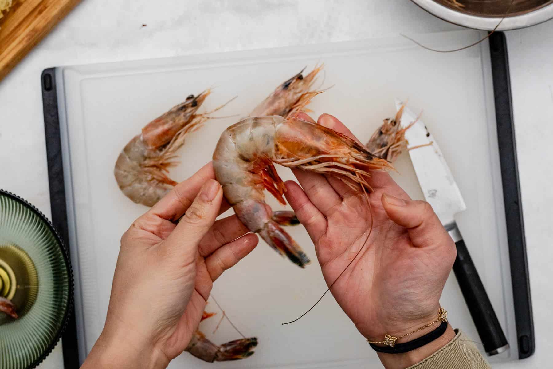 holding shrimp with cutting board behind.