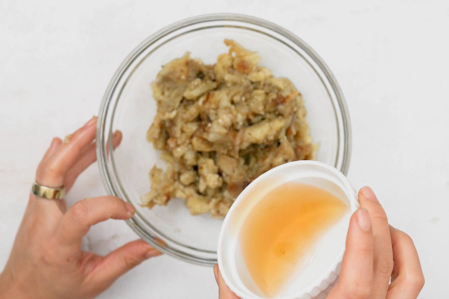adding vinegar to bowl with charred eggplant.