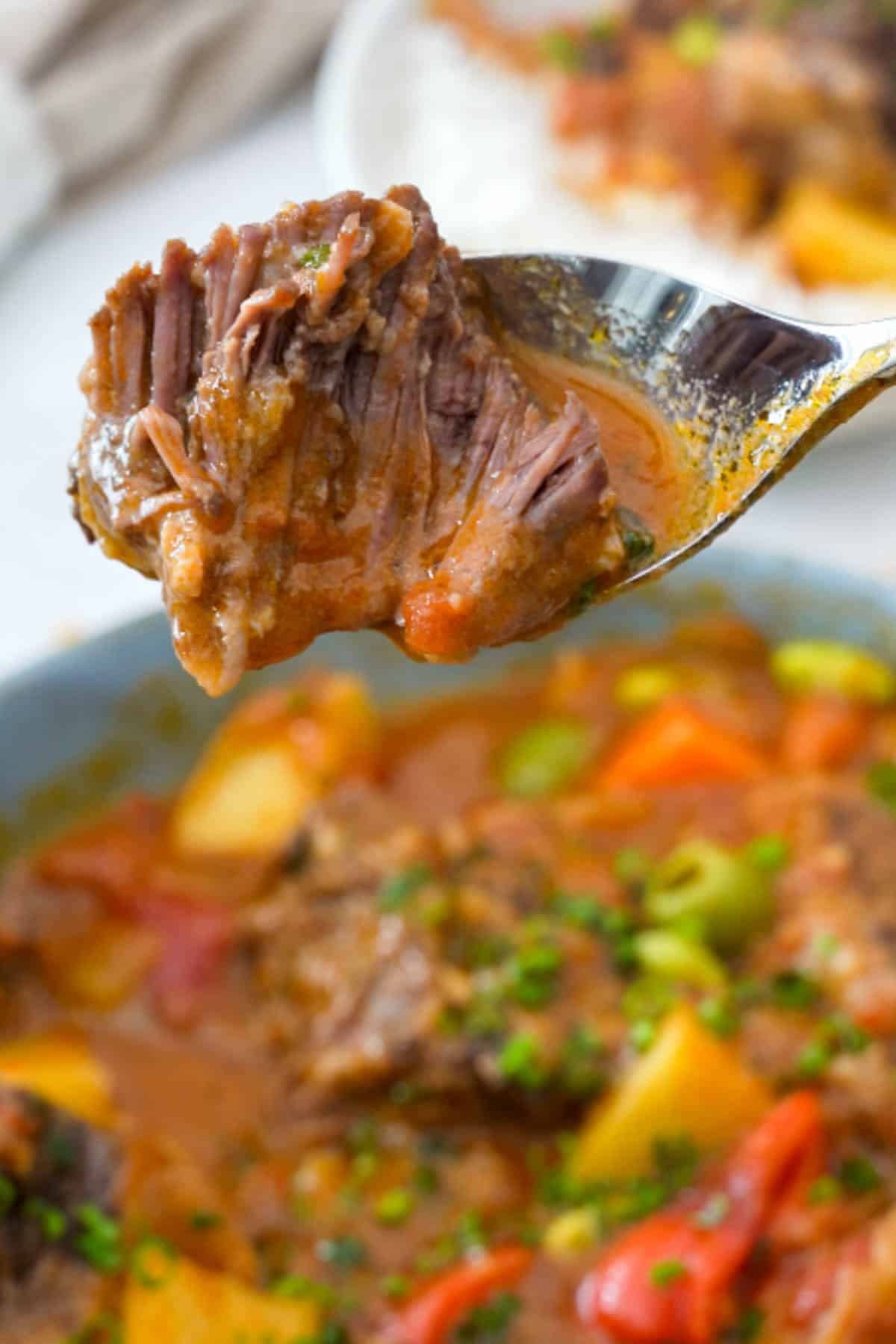close up of tender beef kaldereta on a spoon.
