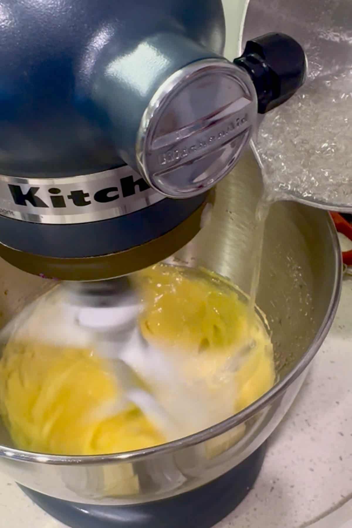 pouring hot sugar into beaten egg yolks in standmixer.