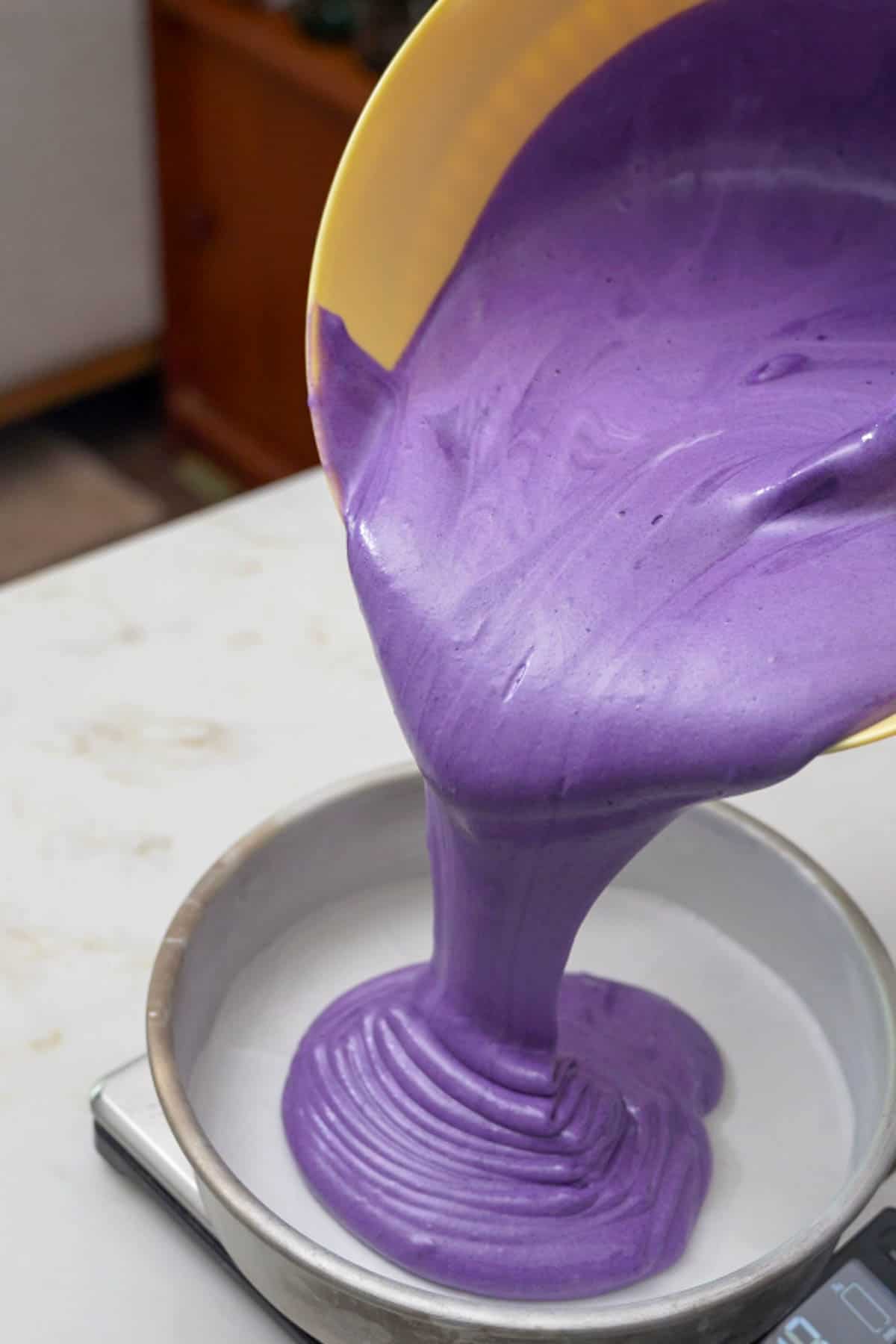 dilling cake pan with ube cake batter.