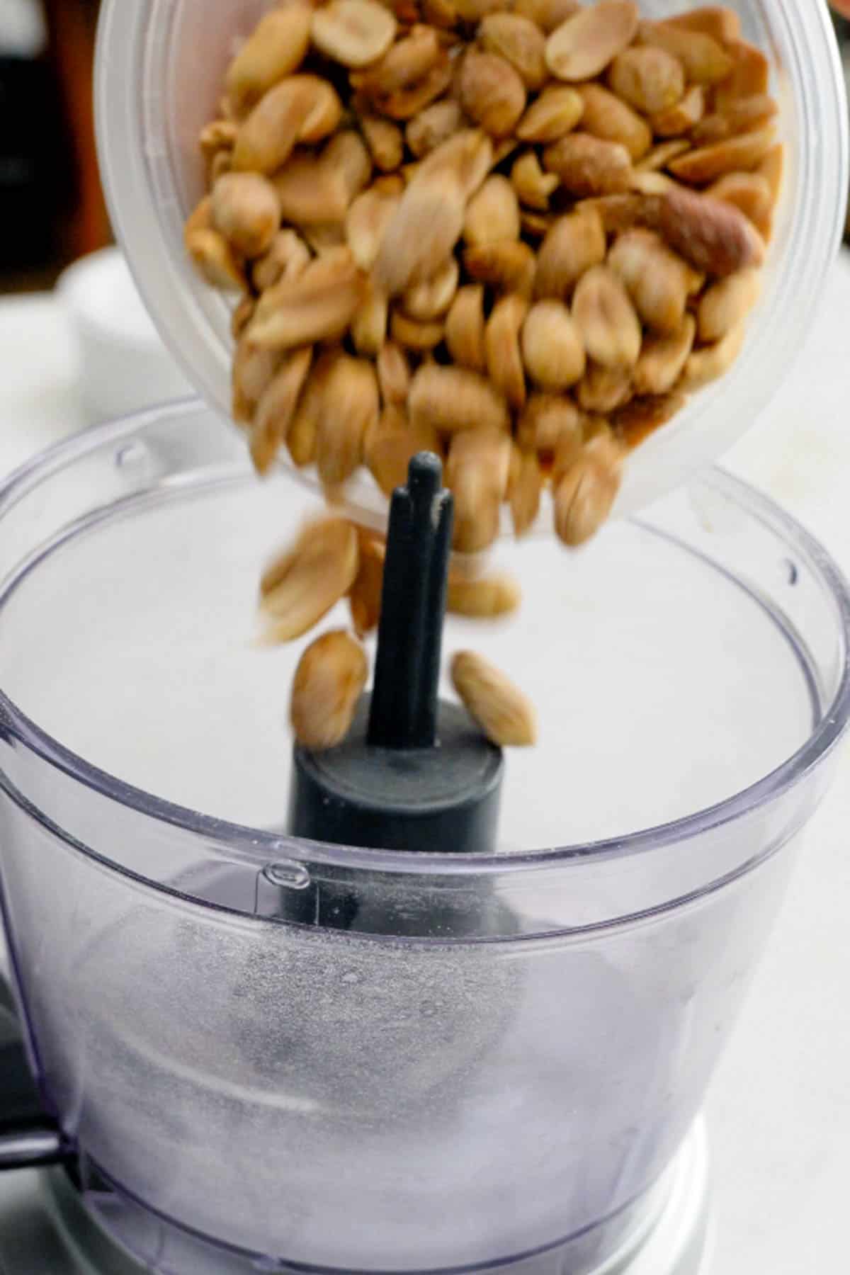 pouring peanuts in food processor.