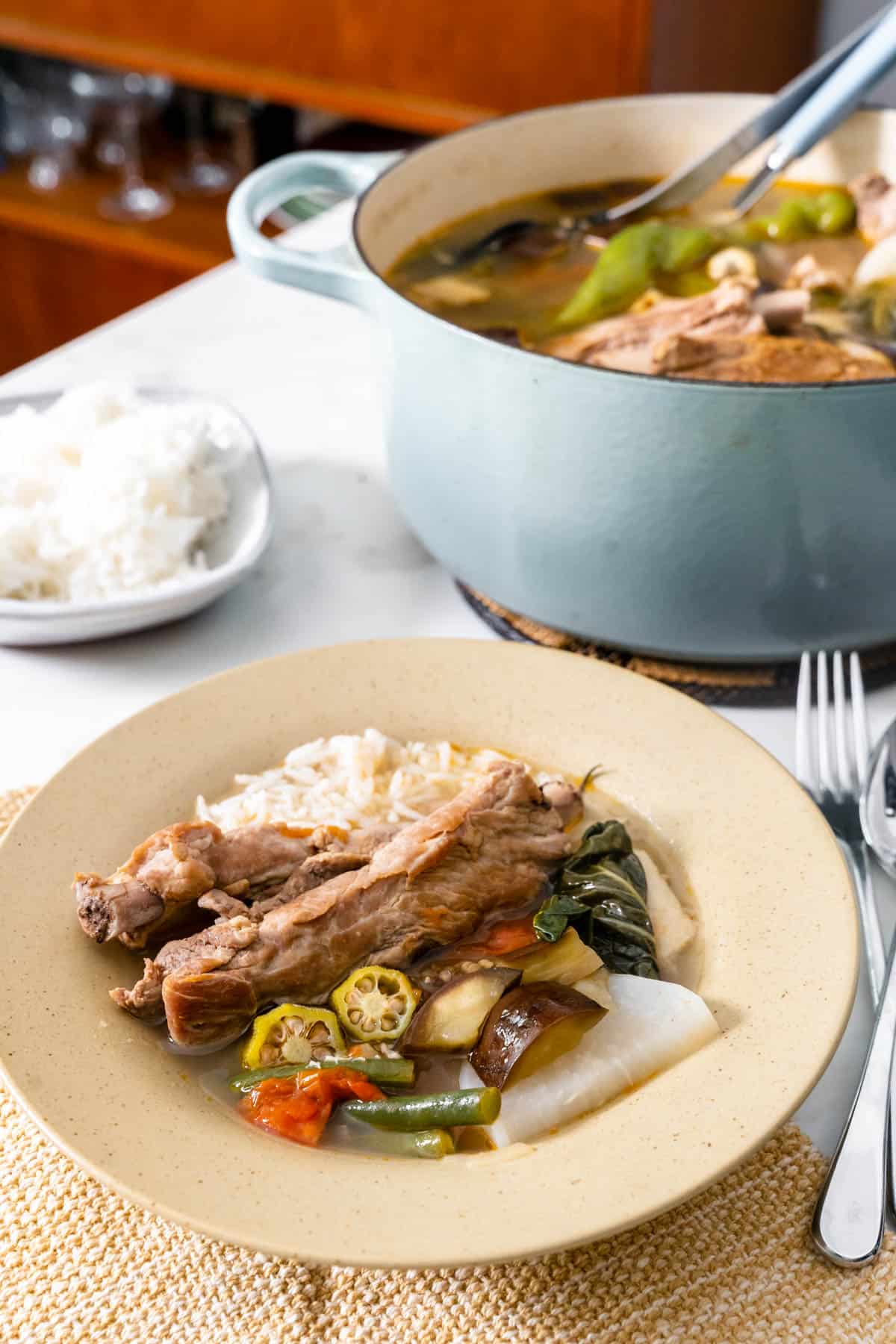 pork sinigang served in a bowl with rice.