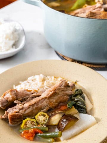 pork sinigang in pot and served in a bowl with rice.