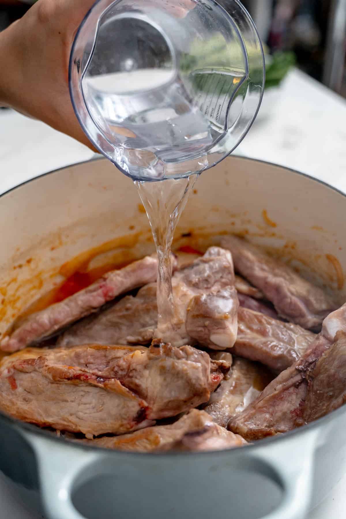 pouring water in pot of ribs.