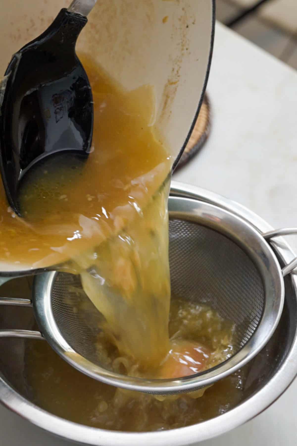 pouring broth in a fine mesh sieve.
