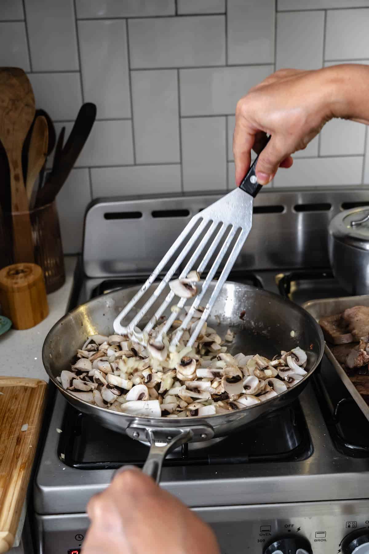 sauteeing mushrooms and onions in a pan.